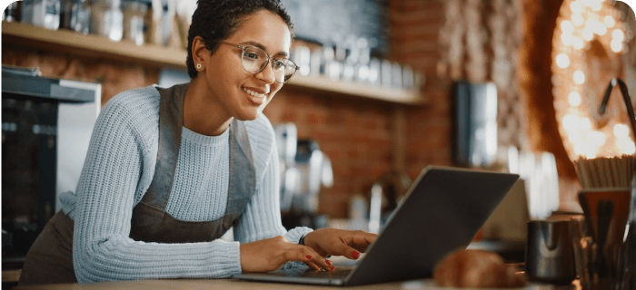 Encargada de restaurante usando el robot de WhatsApp de OlaClick en el notebook